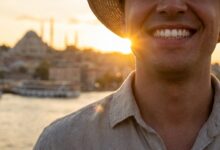 A close-up of a person's bright, healthy smile with a beautifully blurred background showing a scenic view of Istanbul, Turkey at sunset, representing a dental holiday.