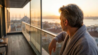 A person viewed from behind, looking out from a modern balcony at a softly blurred, golden sunrise over the Istanbul, Turkey skyline, symbolizing a successful and safe dental tourism trip.