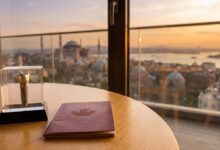 A close-up of a dental implant model and a Canadian passport resting on a table, with a beautifully blurred background of the Istanbul skyline and Bosphorus Strait, symbolizing dental tourism for Canadians in Turkey.
