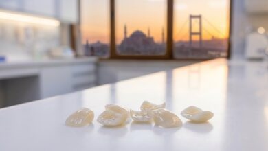 A photorealistic close-up of pristine white dental veneers on a clean surface, with the blurred skyline of Istanbul, Turkey and the Bosphorus visible in the background during a warm sunset.