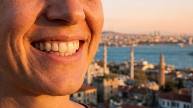 Close-up of a person's flawless, white smile, with a beautiful, sunlit, and blurred Turkish city coastline in the background, representing a successful dental tourism trip.