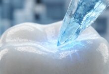 An abstract, photorealistic macro photo visualizing tooth sensitivity, showing a clean white enamel surface being touched by a piece of blue ice, creating a glowing blue reaction at the point of contact.