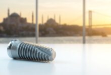 A photorealistic close-up of a modern titanium dental implant on a clean surface, with the beautifully blurred skyline of Istanbul, Turkey, visible through a window in the background during a warm sunrise.