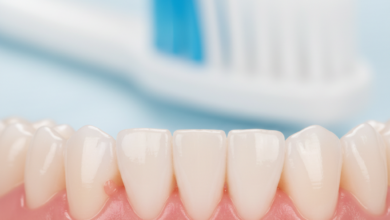 Close-up photorealistic image of healthy pink gums and white teeth, with a blurred soft-bristled toothbrush head in the background, symbolizing oral hygiene and gum disease prevention.