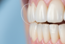 Close-up of dental floss carefully cleaning between two healthy, white teeth near pink gums in a clean, blurred environment, emphasizing good oral hygiene.