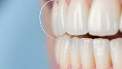 Close-up of dental floss carefully cleaning between two healthy, white teeth near pink gums in a clean, blurred environment, emphasizing good oral hygiene.