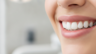 A close-up, photorealistic image of a person's lower face, focusing on a healthy, confident smile with perfectly aligned, naturally white teeth. The background is a softly blurred, clean, and modern dental office environment, conveying professionalism and advanced care. There is no text visible in the image.