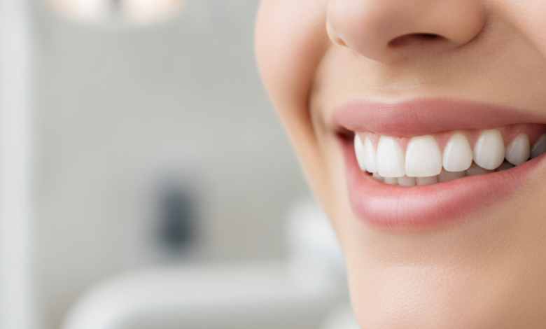 A close-up, photorealistic image of a person's lower face, focusing on a healthy, confident smile with perfectly aligned, naturally white teeth. The background is a softly blurred, clean, and modern dental office environment, conveying professionalism and advanced care. There is no text visible in the image.
