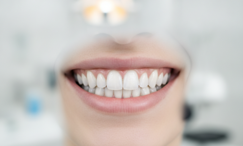 Close-up of a person's radiant, perfectly aligned, and brilliant white teeth, showcasing a flawless smile. The background is a softly blurred, modern, and clean dental clinic.